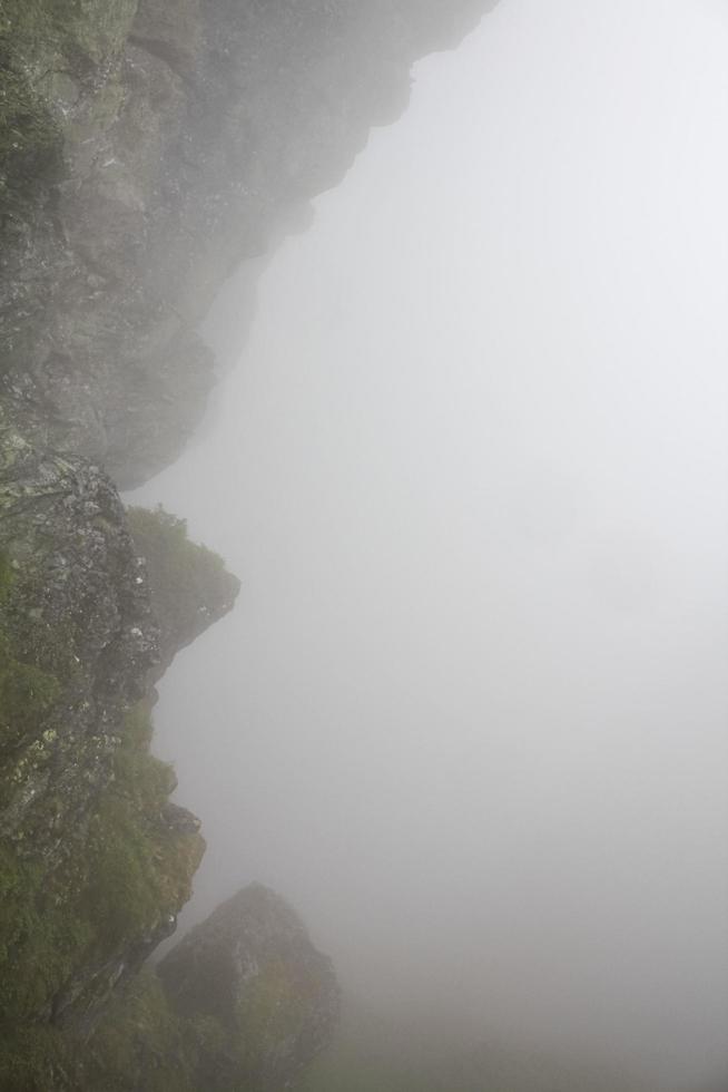 brouillard, nuages, rochers et falaises sur la montagne veslehodn veslehorn, norvège. photo