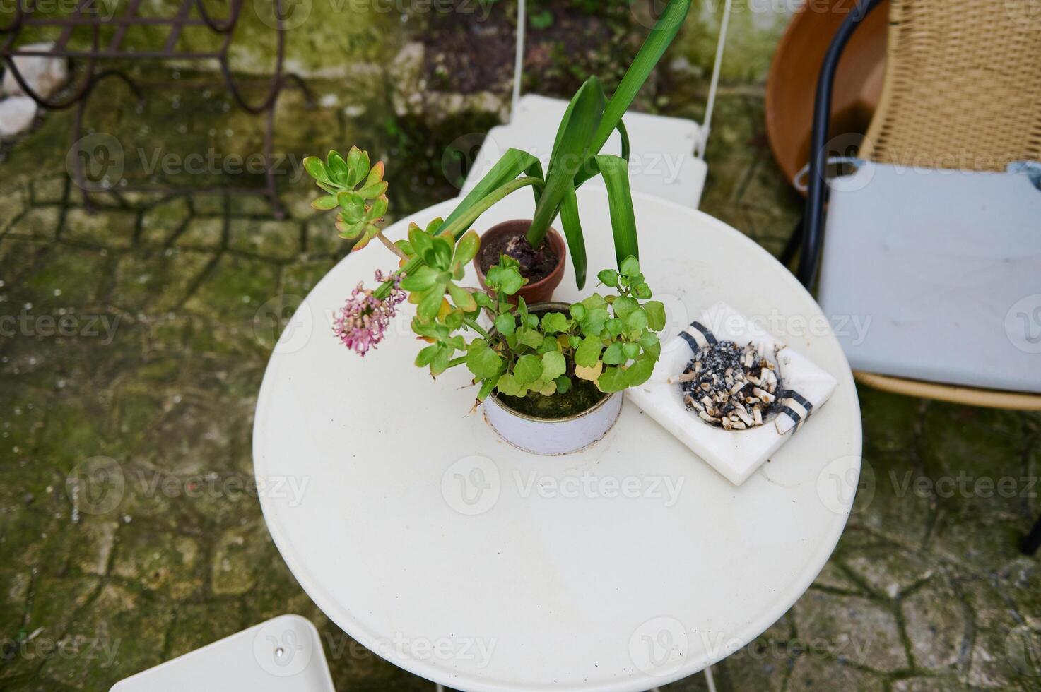 Haut vue cendrier avec cigarette mégots sur le blanc table avec chaise dans le jardin. le concept de poumon cancer maladies photo