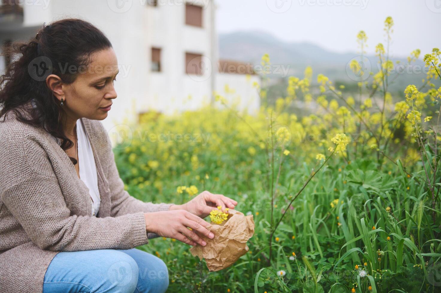 sur de soi Jeune femme rassemblement herbes et les plantes pour médical utiliser, collecte fleurs dans une papier sac dans le la nature photo