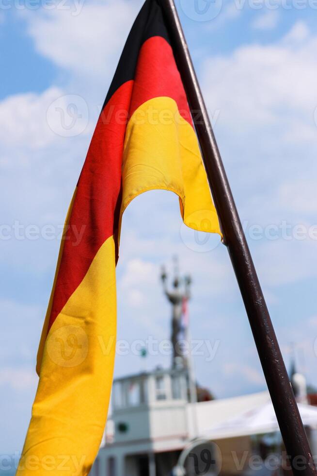 drapeau de Allemagne sur le navire agitant dans le vent plus de le constance Lac Bodensee. allemand nationale drapeau sur une bateau. flou statue impérie, touristique bateau, bleu ciel, blanc des nuages. sur le arrière-plan, photo