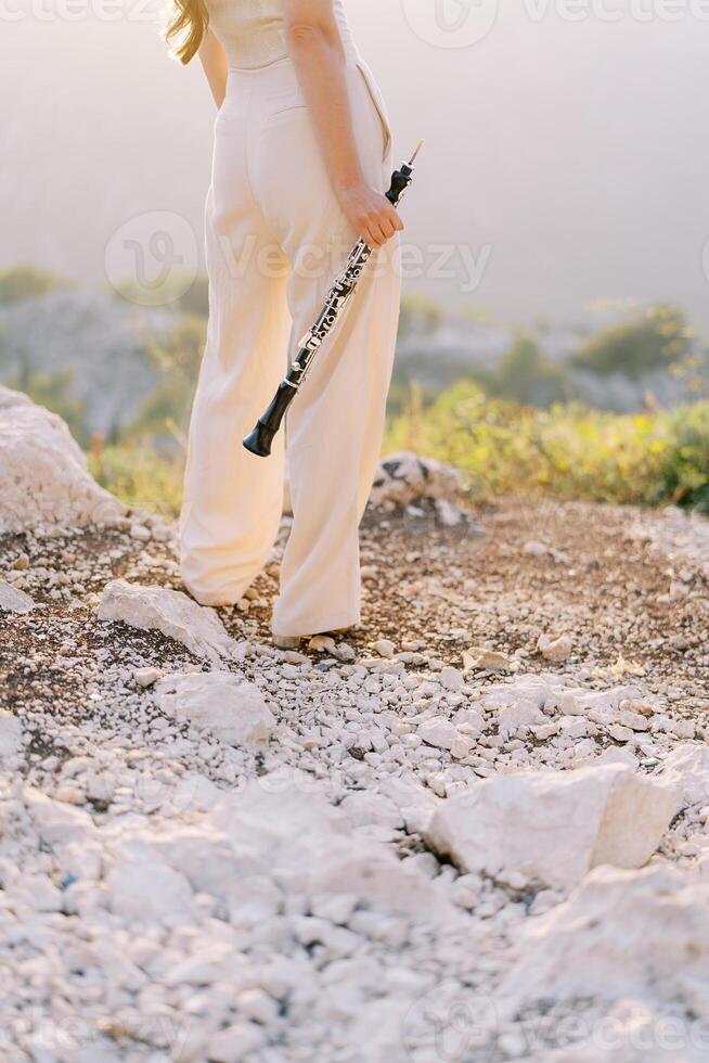 fille-musicienne des stands dans le montagnes avec une flûte dans sa main. tondu photo