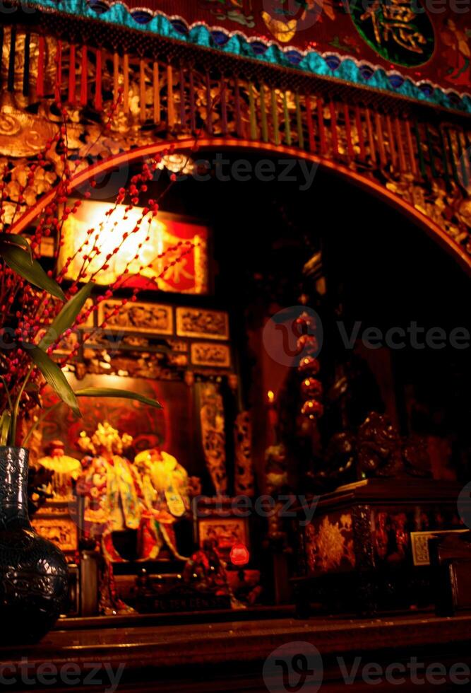 le prière pièce contient une statue de une chinois Dieu avec brûlant rouge encens photo