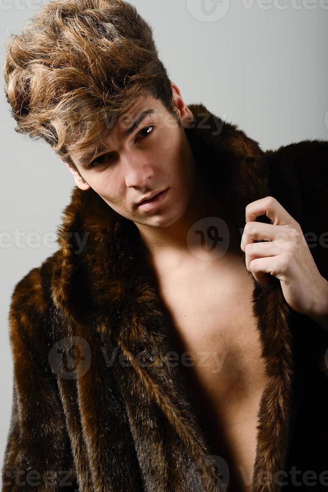 séduisant jeune homme portant un manteau de fourrure avec une coiffure moderne photo