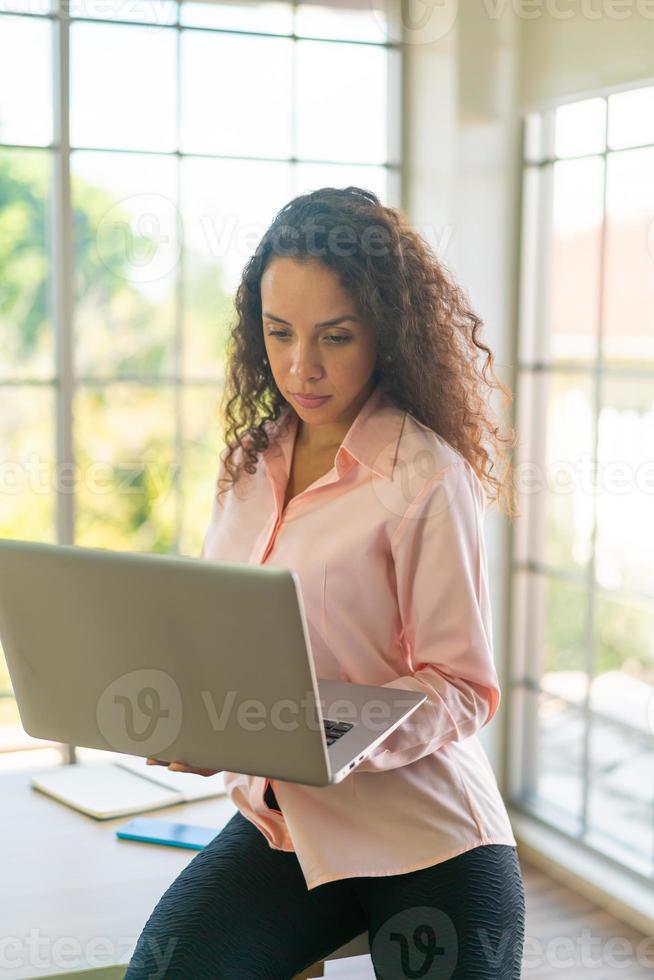 femme latine travaillant avec un ordinateur portable sur un espace de travail photo