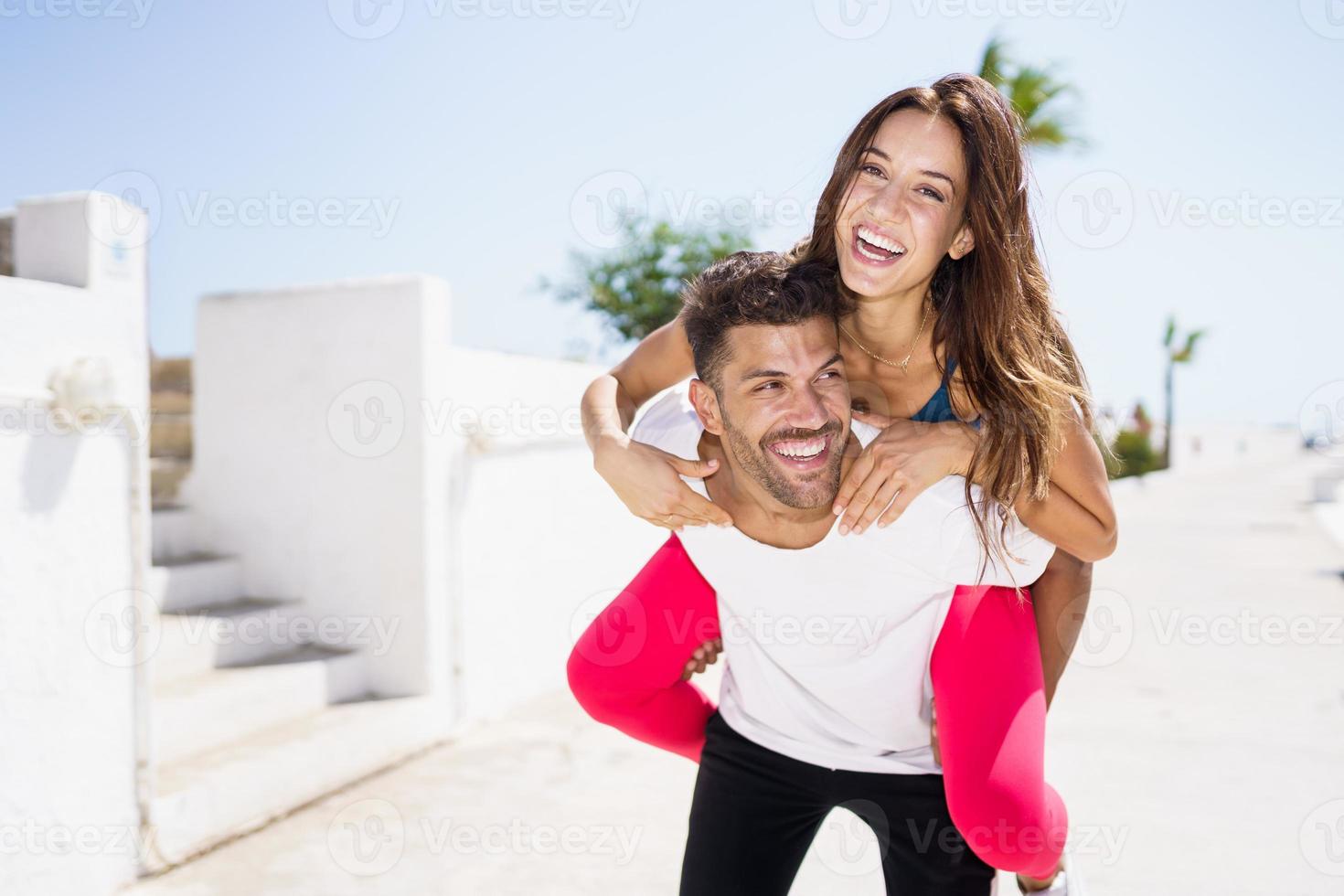 homme portant sa petite amie sur le ferroutage portant des vêtements de sport. photo