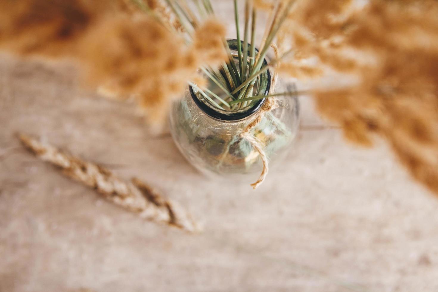 nature morte d'un bouquet de fleurs séchées dans une bouteille en verre sur une table en bois. place pour le texte ou la publicité. vue d'en-haut photo