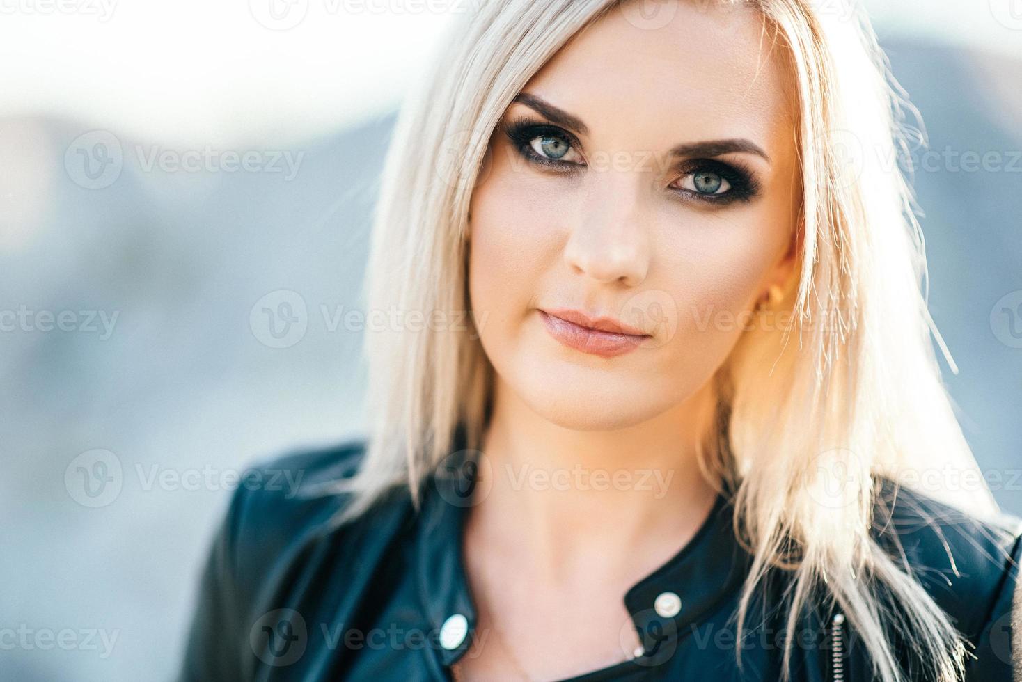 fille blonde dans un costume de pantalon noir aux yeux bleus sur le fond d'une carrière de granit photo