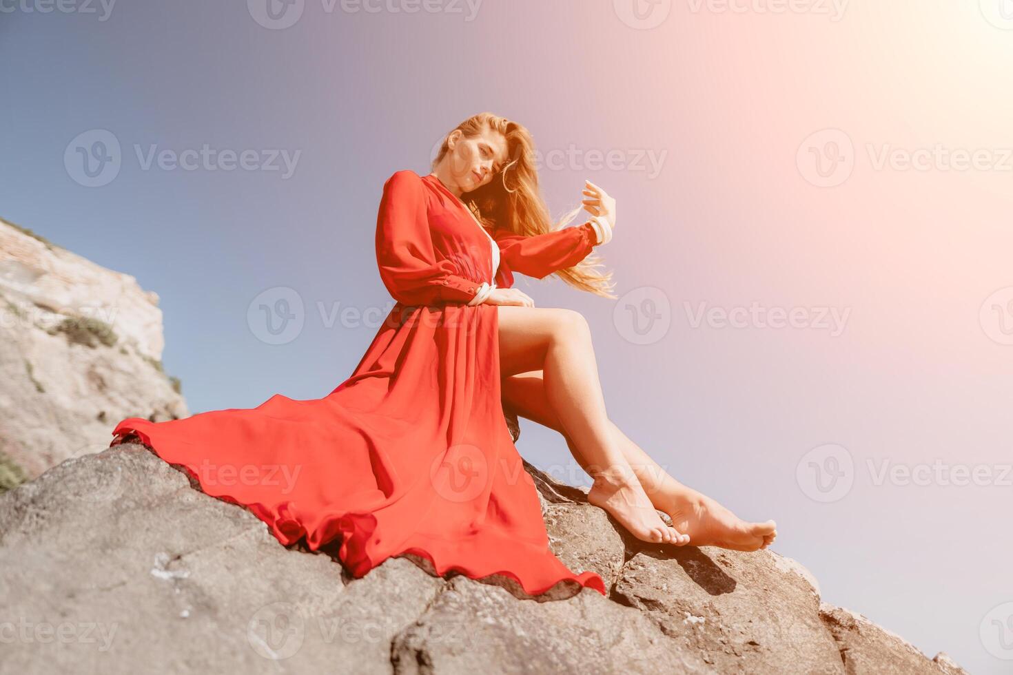 femme Voyage mer. Jeune content femme dans une longue rouge robe posant sur une plage près le mer sur Contexte de volcanique rochers, comme dans Islande, partage Voyage aventure périple photo