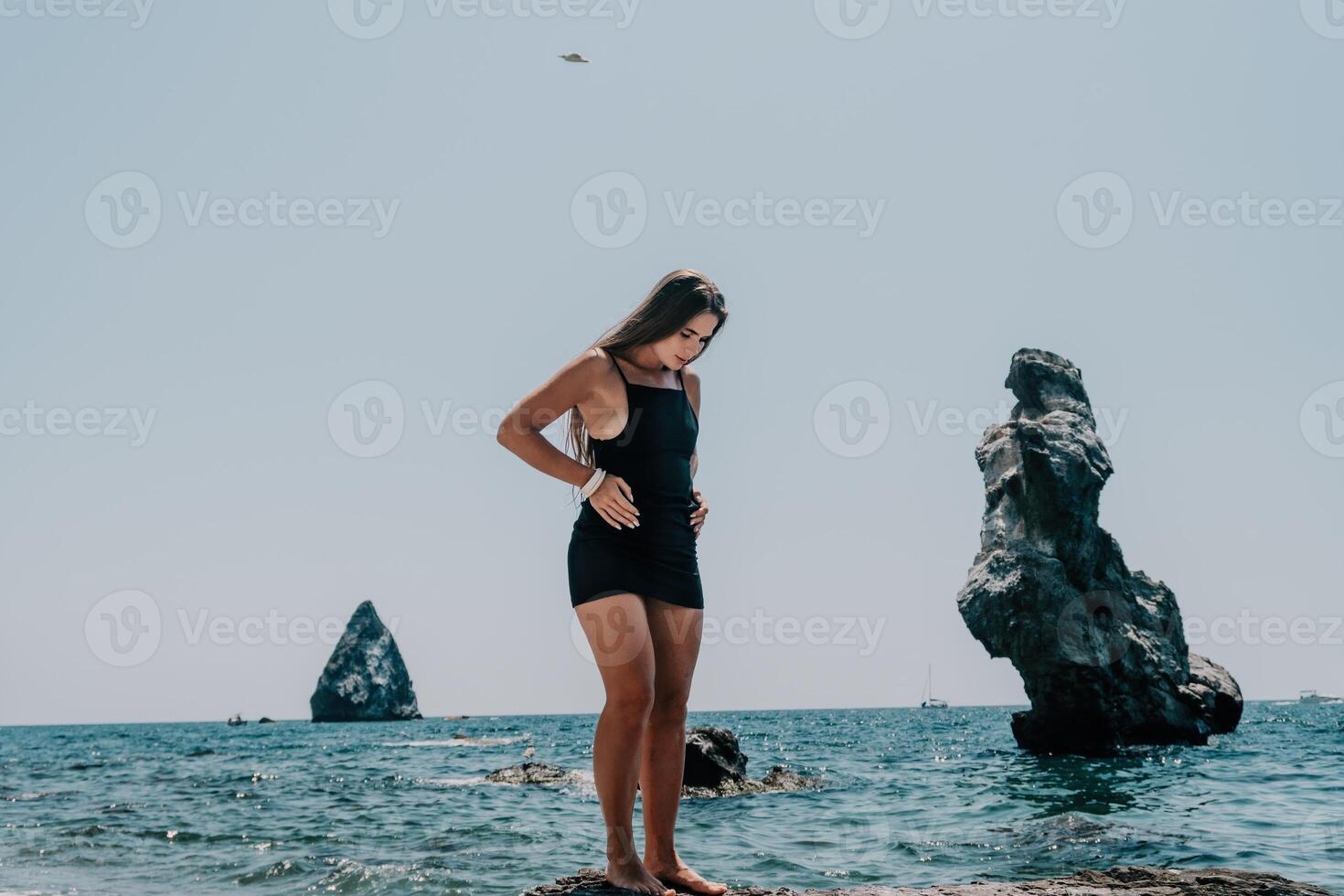 femme été Voyage mer. content touristique dans chapeau prendre plaisir prise image en plein air pour souvenirs. femme voyageur posant sur le plage à mer entouré par volcanique montagnes, partage Voyage aventure périple photo