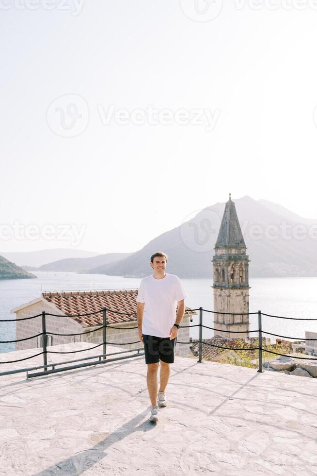 souriant gars des promenades le long de le observation plate-forme près le église. perast, Monténégro photo