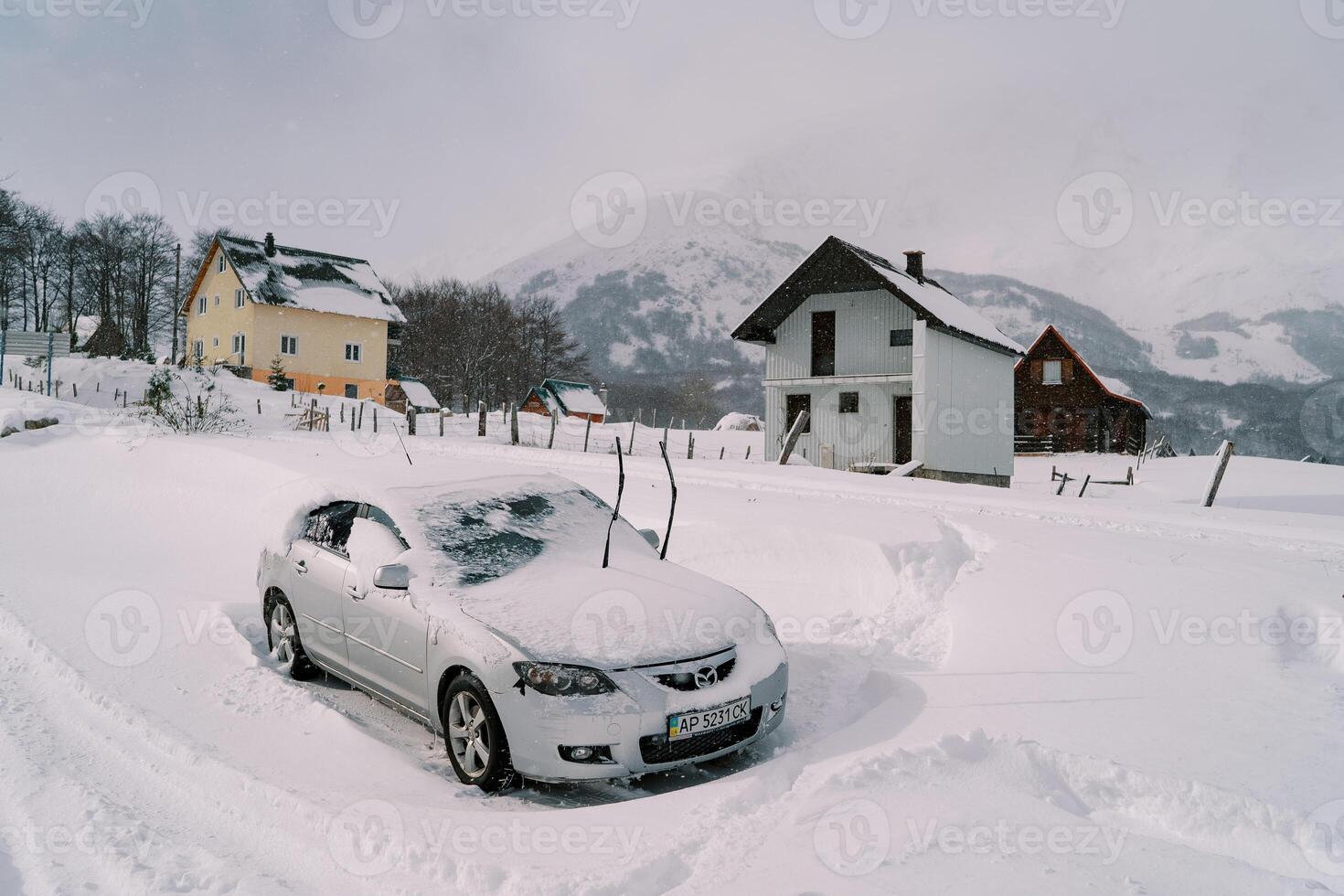 couvert de neige voiture avec élevé pare-brise essuie-glaces des stands près coloré Maisons à le pied de le montagnes photo