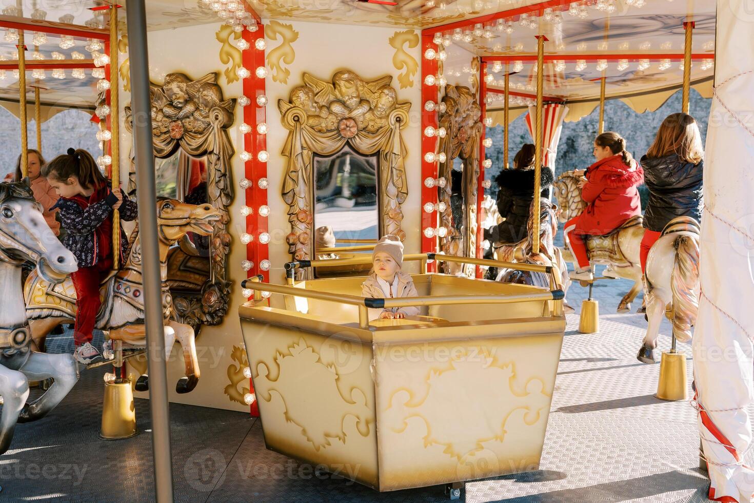 peu fille est assis sur une carrousel siège suivant à les enfants équitation jouet les chevaux photo