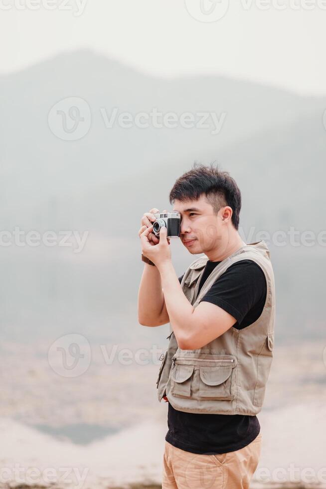 Jeune homme avec une ancien caméra capture le beauté de le en plein air sur une brumeux journée. photo