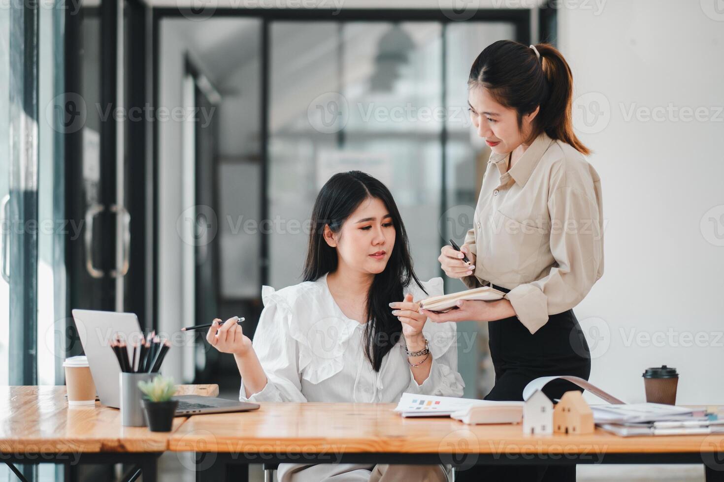 deux engagé femelle collègues la revue Remarques et discuter projet détails, avec un prise le conduire dans expliquant, mise en évidence le synergie dans une professionnel équipe environnement. photo