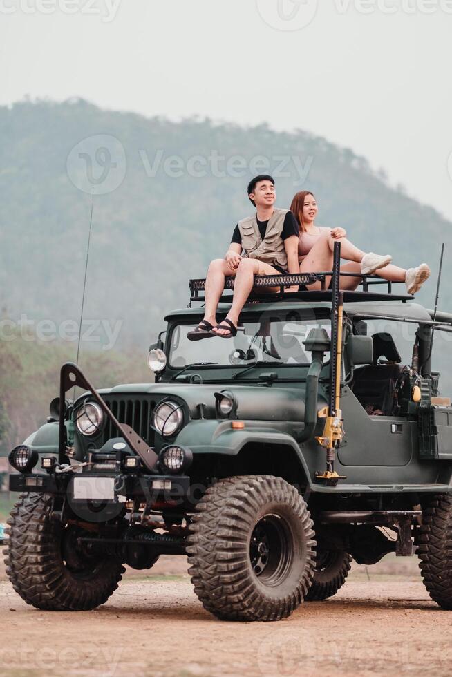 aventureux couple est perché un haut une robuste voiture, le femme montrer du doigt vers le horizon, prêt pour leur suivant hors route exploration. photo