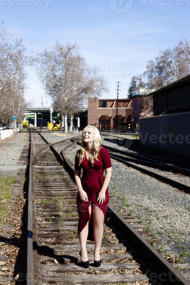 blond femme permanent sur rail route des pistes rouge robe photo