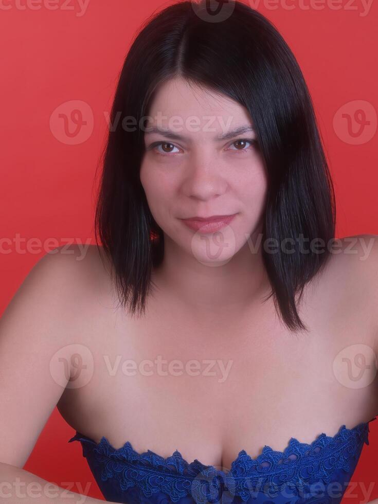 Jeune femme avec foncé cheveux dans bleu corset sur rouge Contexte photo