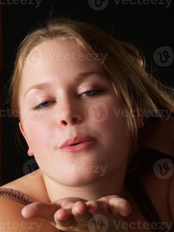 caucasien blond femme sur noir Contexte soufflant baiser photo