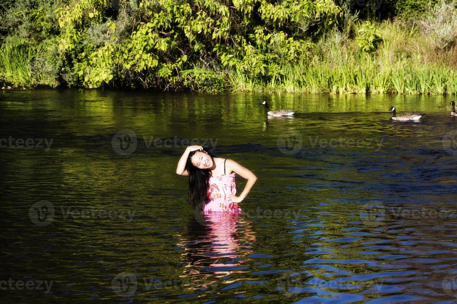 souriant Japonais américain femme permanent dans rivière avec oies photo