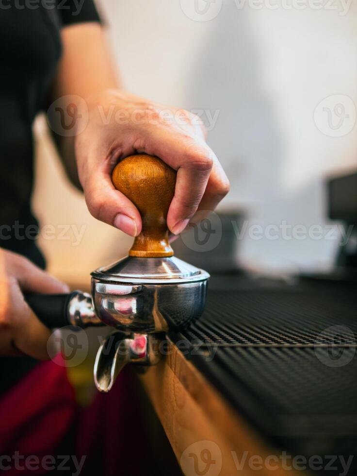 main de une barista en portant une porte-filtre et une café altérer fabrication un Expresso café. barista presses sol café en utilisant une altérer dans une café magasin photo