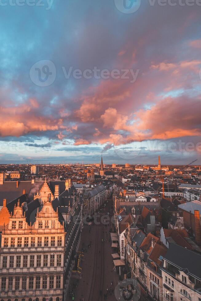 en train de regarder le le coucher du soleil plus de Gand de le historique la tour dans le ville centre. romantique couleurs dans le ciel. rouge lumière éclairant Gand, Flandre région, Belgique photo