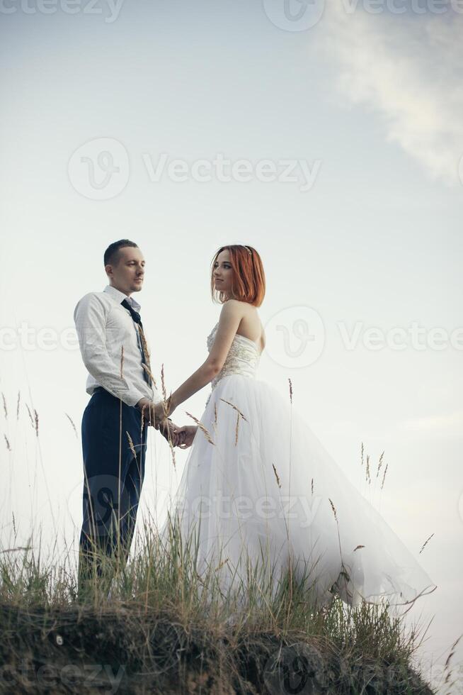 élégant doux élégant jeune marié et la mariée près rivière ou lac. mariage couple dans l'amour photo