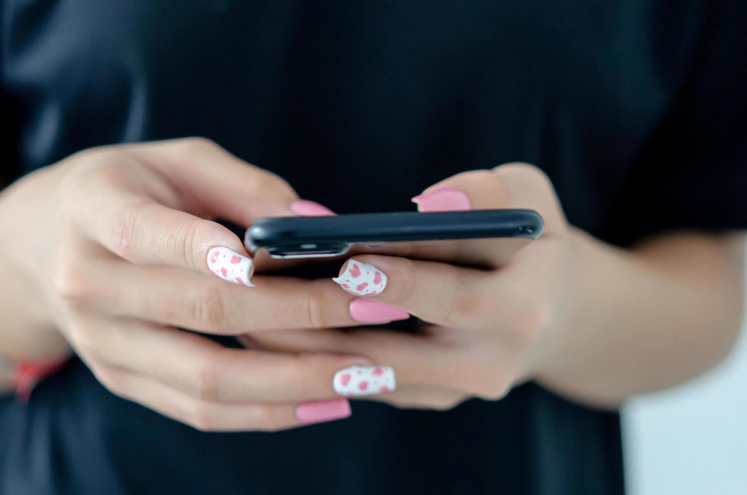 main féminine tenant un téléphone avec un beau vernis à ongles rose photo