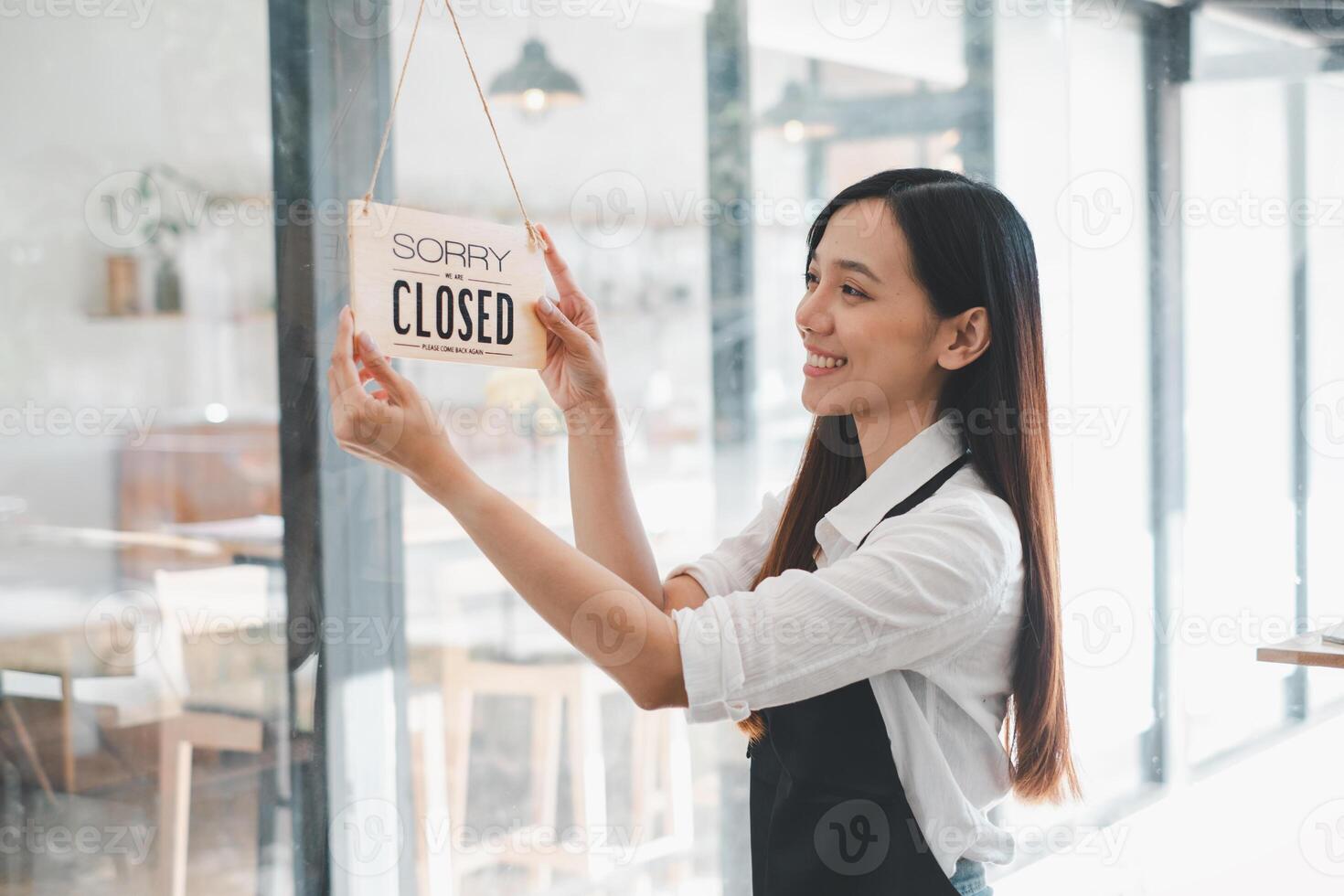 une café propriétaire affiche une 'Désolé nous sont fermé' signe avec une contenu sourire, marquage le fin de une épanouissant journée de affaires dans sa accueillant établissement. photo