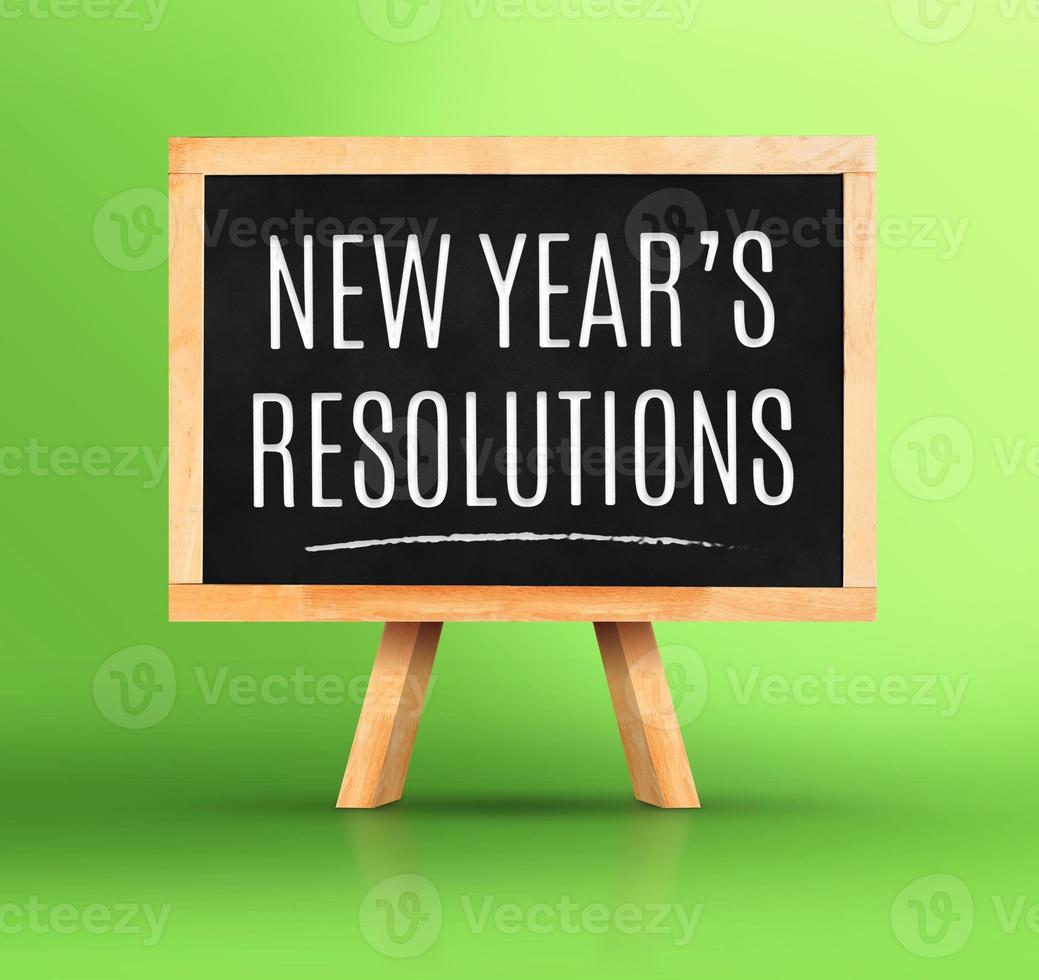 Mot de résolutions du nouvel an sur tableau noir avec chevalet sur vert vif photo