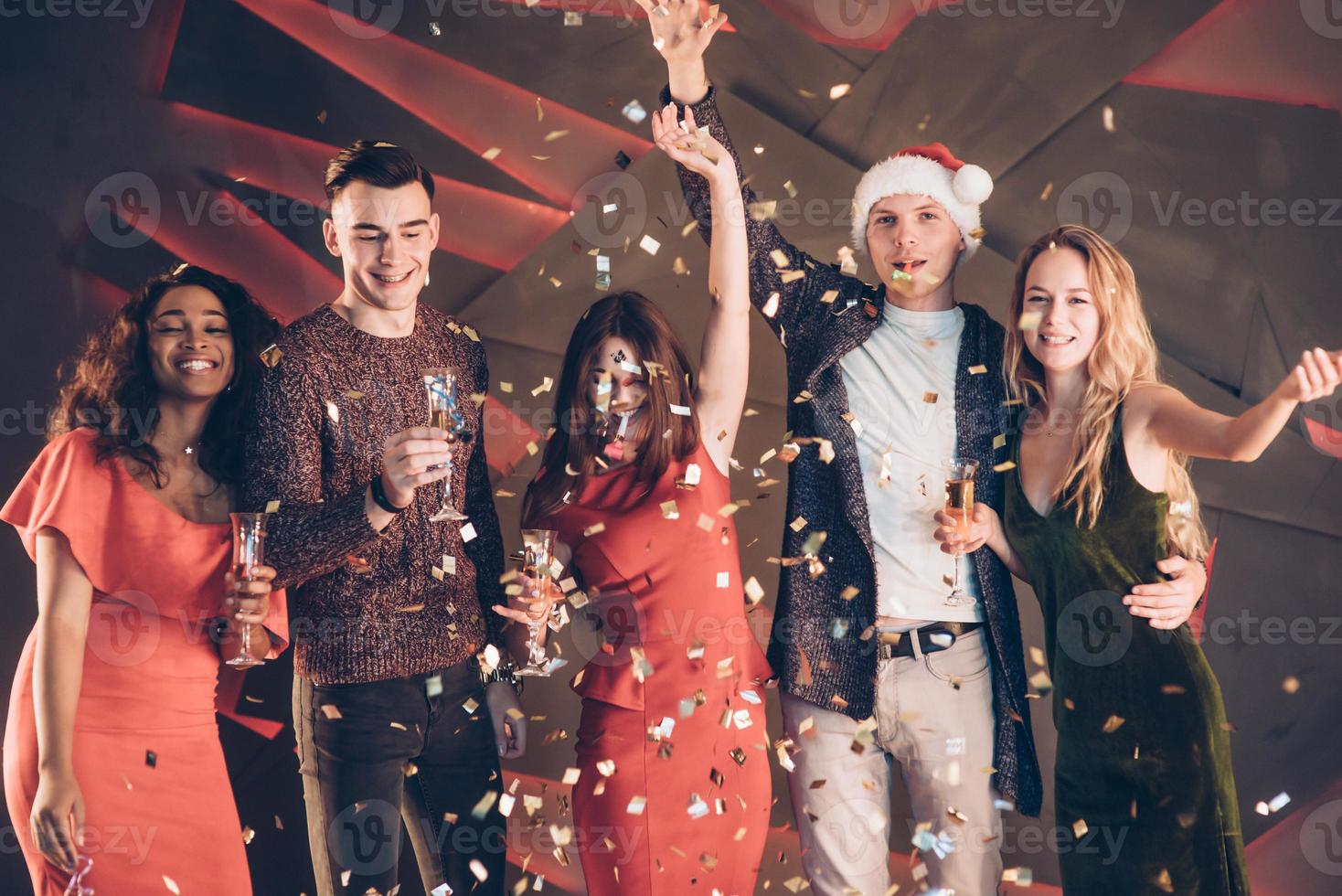 l'air dans les confettis. cinq bons amis dans les bons vêtements sont à la fête du nouvel an photo