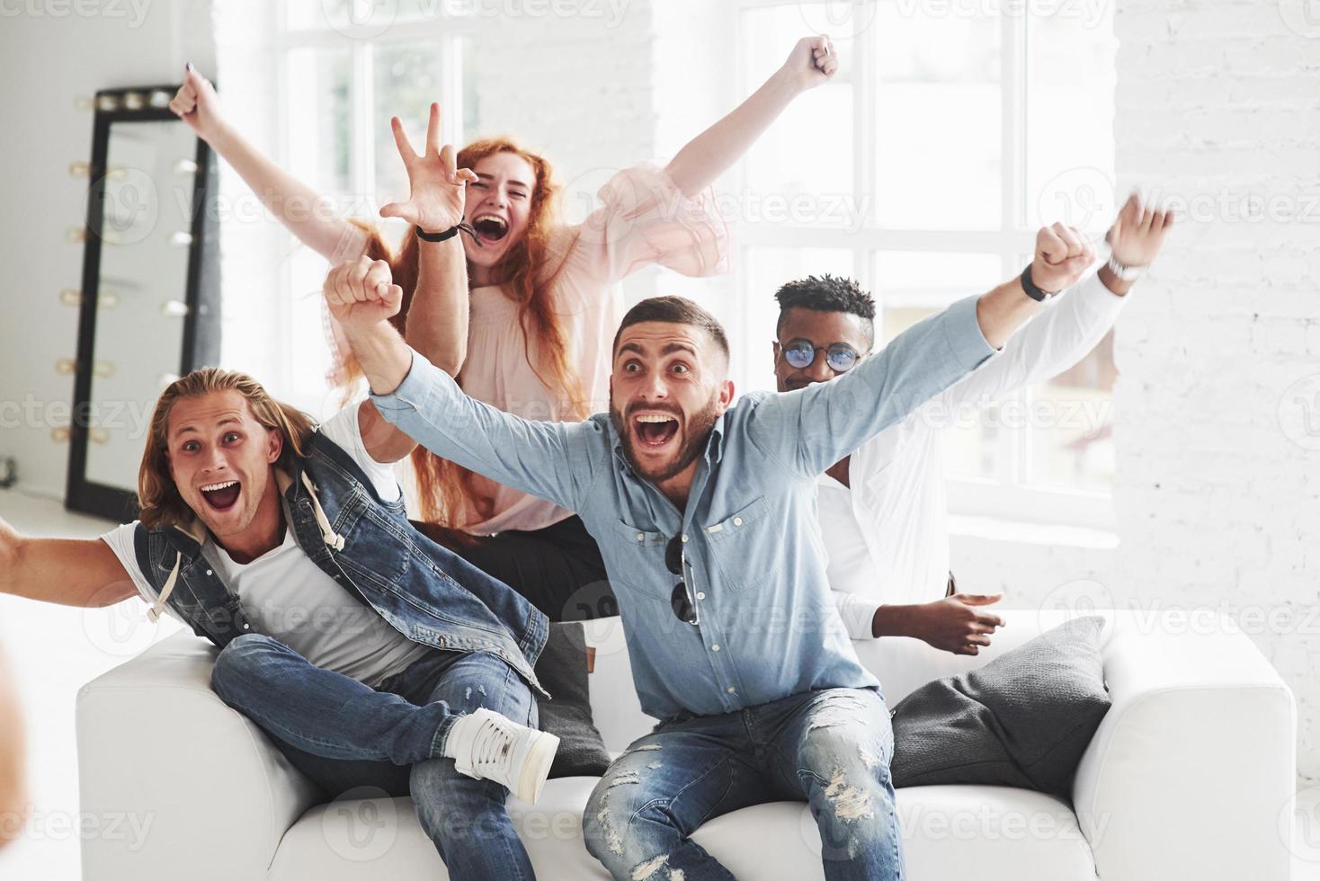 soyons un peu fous. les amis de bureau passent du bon temps assis et allongés sur le canapé blanc photo