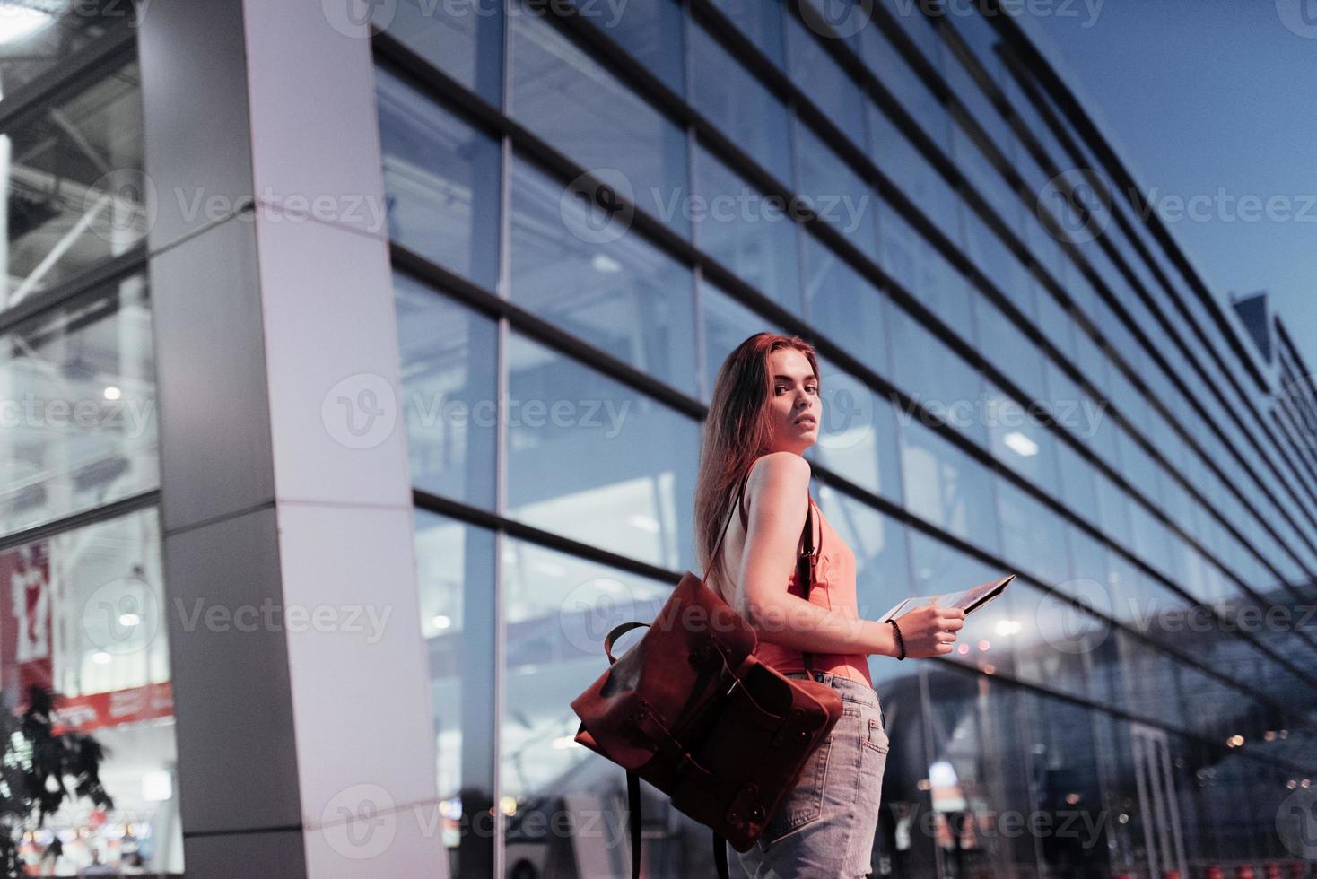 photo de dos. jolie fille marchant près de l'aéroport et regardant la carte dans ses mains