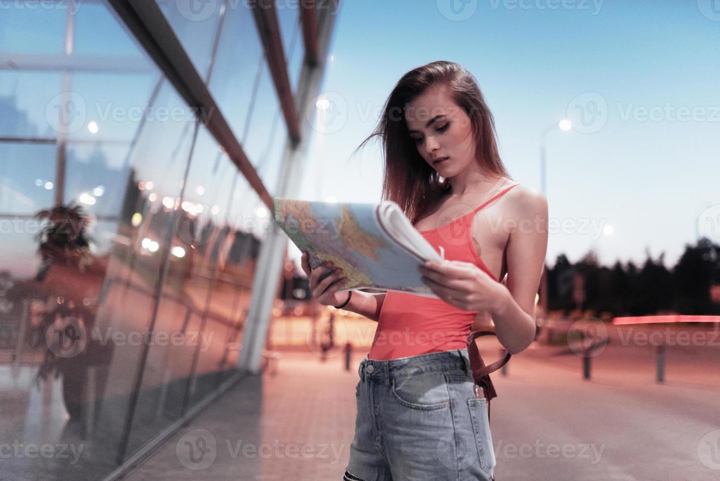 étudier de nouvelles voies. conception du voyage. jolie fille marchant près de l'aéroport et regardant la carte dans ses mains photo