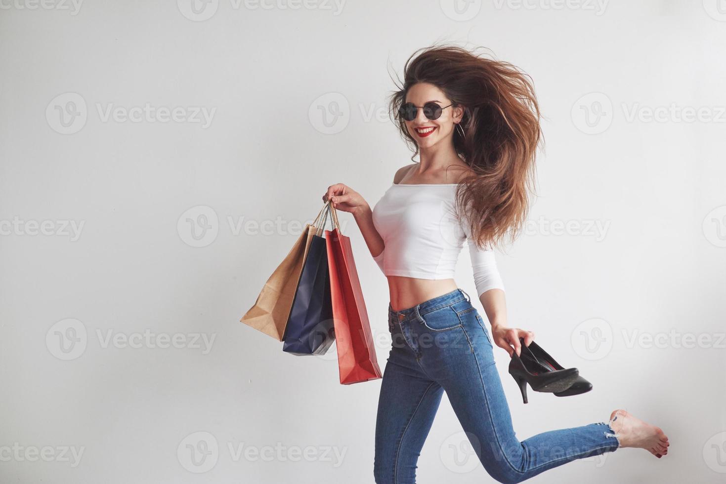 courir vers la cabine d'essayage. juste du shopping. jeune femme élégante tenant les paquets avec des vêtements et des talons photo