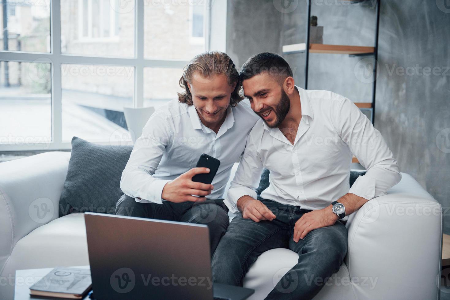 bonne humeur. deux businessman sitting in front of laptop parlant de leurs plans photo