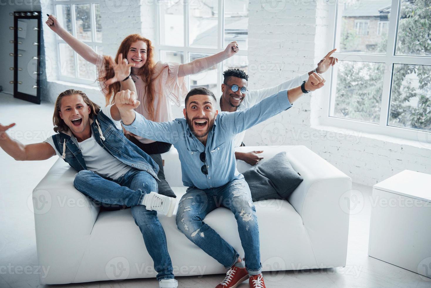 amis heureux souriant, levant les mains et regardant dans la caméra photo