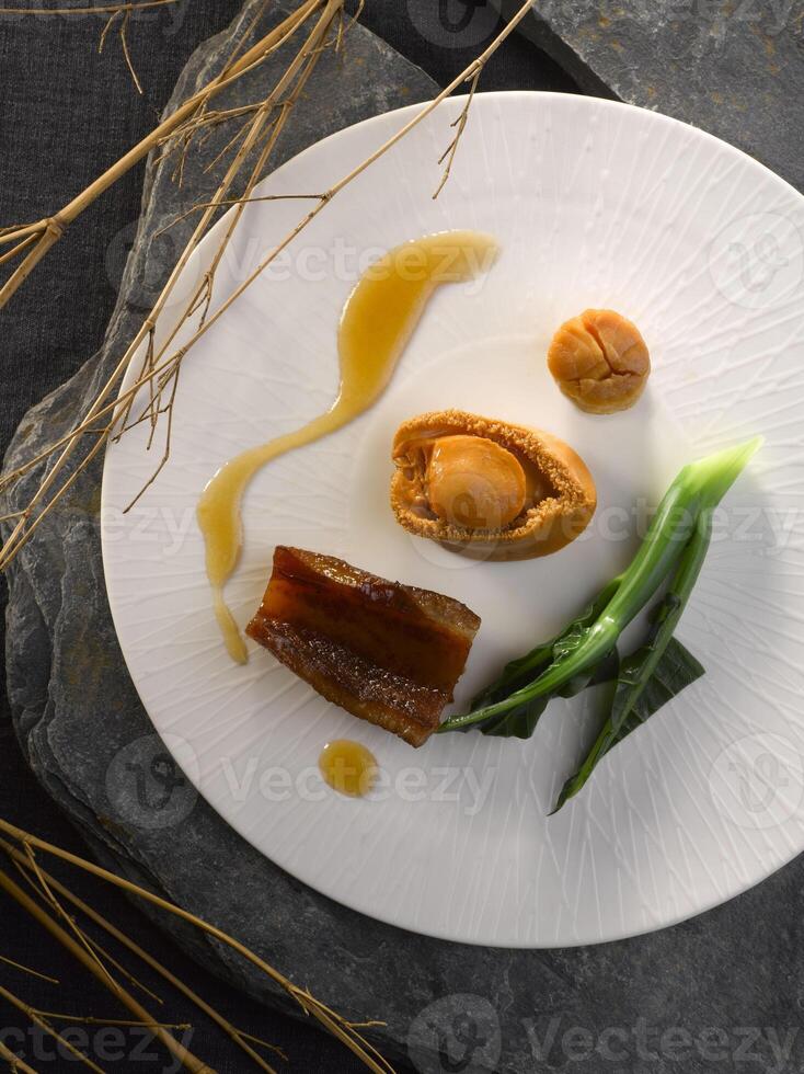 braisé entier ormeau avec conpo et poisson gueule dans marron sauce servi dans plat isolé sur table Haut vue de nourriture photo