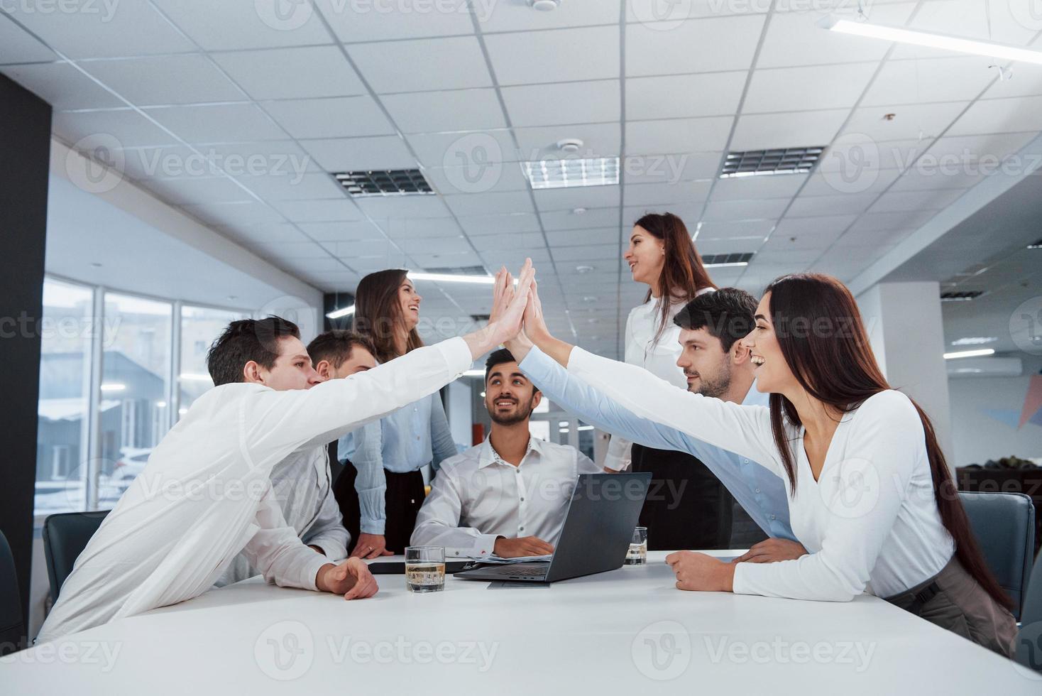 high five à tous. la tâche est finie. groupe d'employés de bureau heureux de battre leurs propres records et de réussir photo