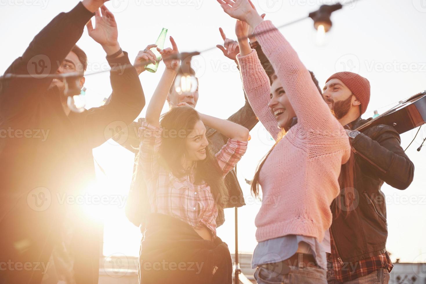 conception du parti. les mains en l'air. les jeunes passent une journée d'automne ensoleillée sur le toit avec guitare et boissons photo