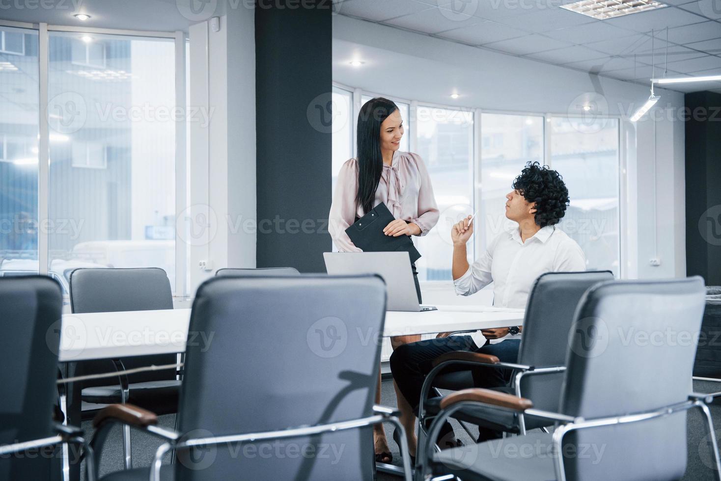 jeunes professionnels. collègues joyeux dans un bureau moderne souriant lorsqu'ils font leur travail à l'aide d'un ordinateur portable photo