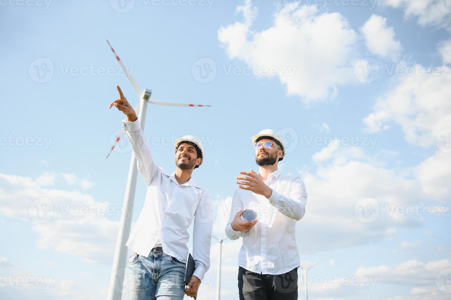 deux ingénieurs discuter contre turbines sur vent turbine cultiver. photo