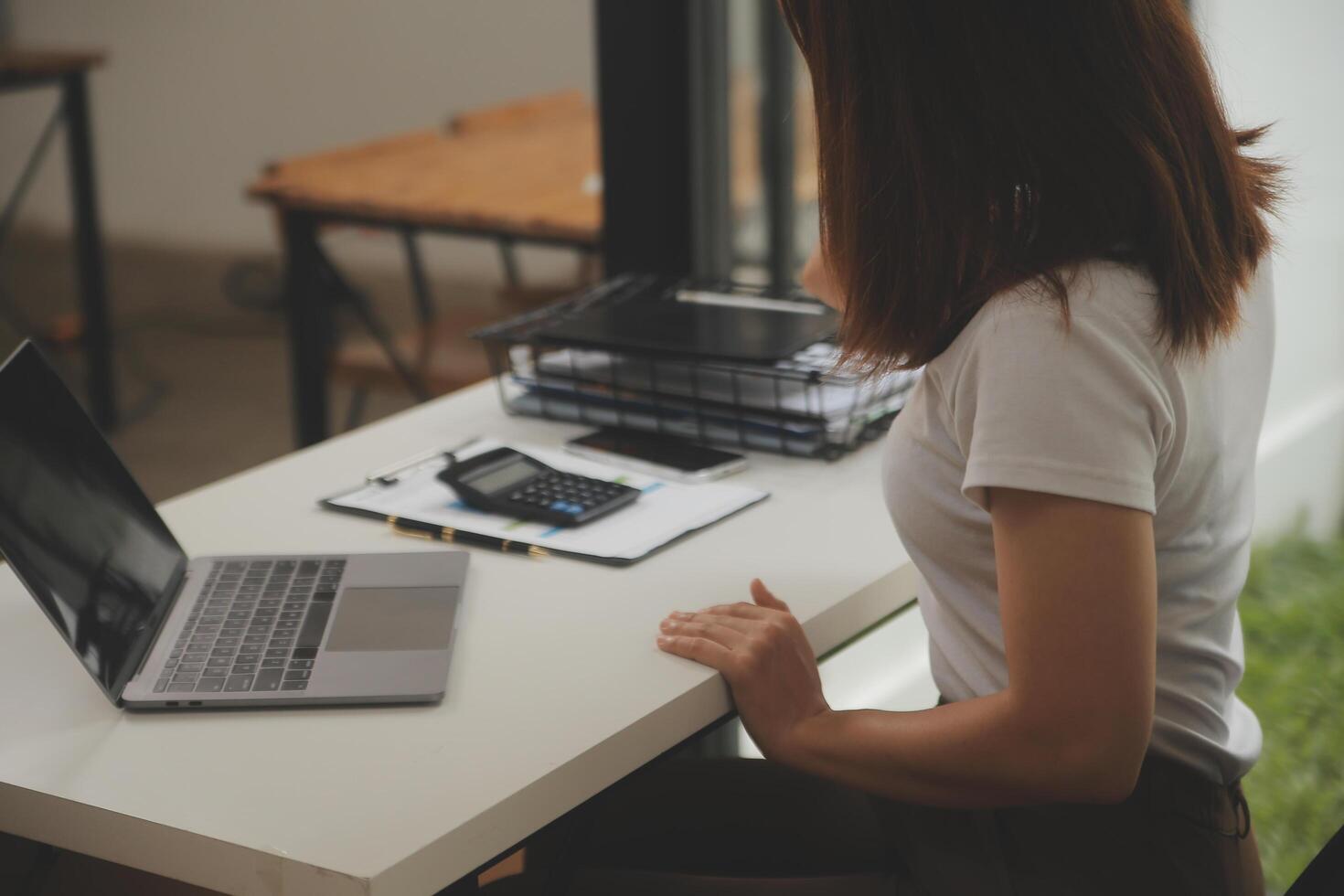 coup de une asiatique Jeune affaires femelle travail sur portable dans sa poste de travail. photo