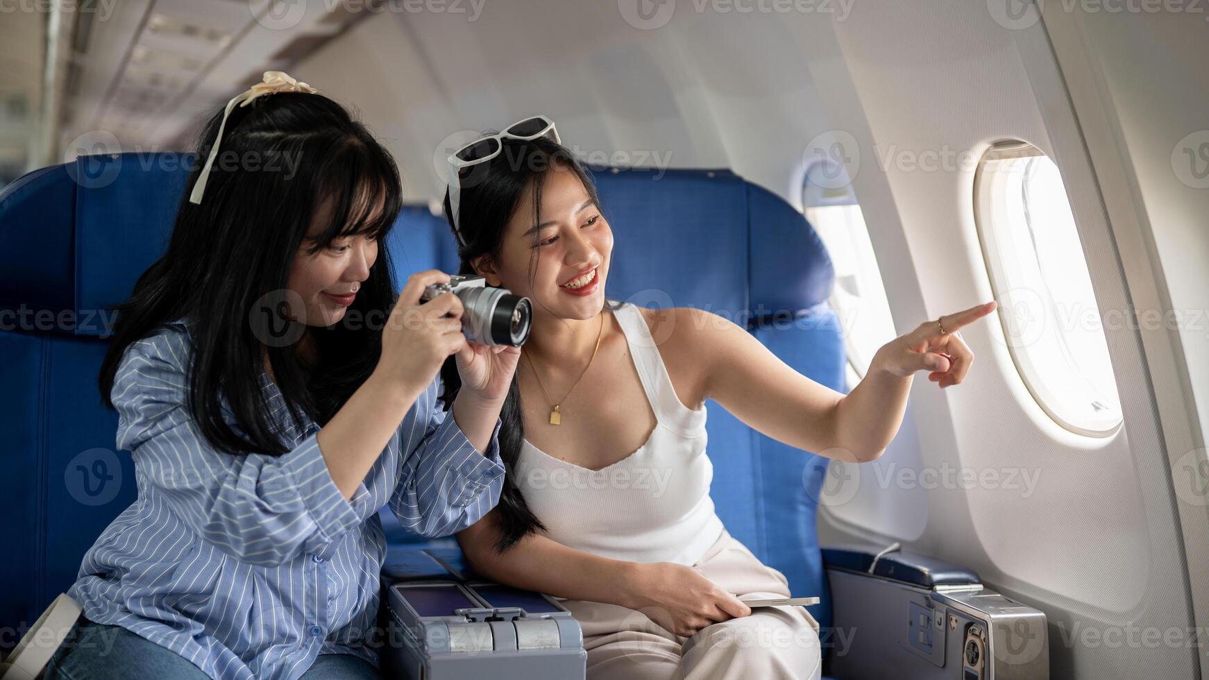 deux de bonne humeur Jeune asiatique femelle copains sont profiter parlant et prise des photos pendant le vol.