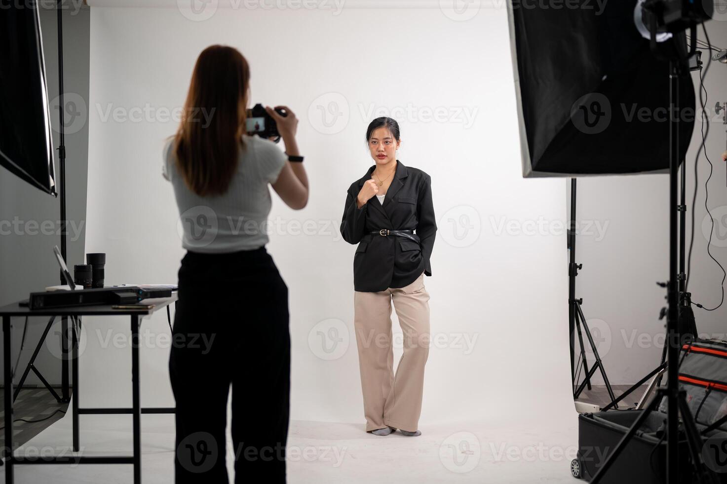 un attrayant asiatique femelle modèle est posant pour une photographe dans une moderne mode studio. photo