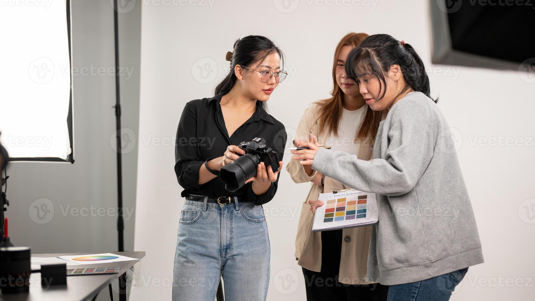 une femelle photographe est parlant et montrant images sur le caméra à sa équipe, travail dans le studio photo