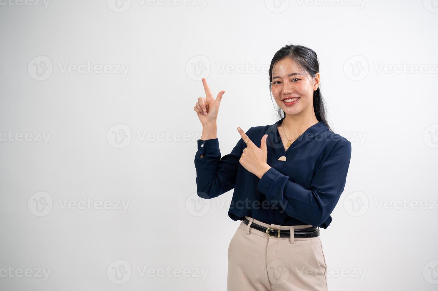 attrayant asiatique femme est montrer du doigt sa indice les doigts en haut à un vide espace, blanc studio Contexte. photo