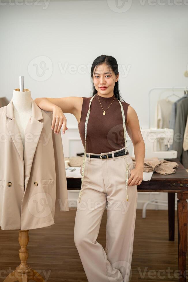 une sur de soi asiatique femelle mode designer est permanent dans sa atelier studio avec une tailleur factice. photo