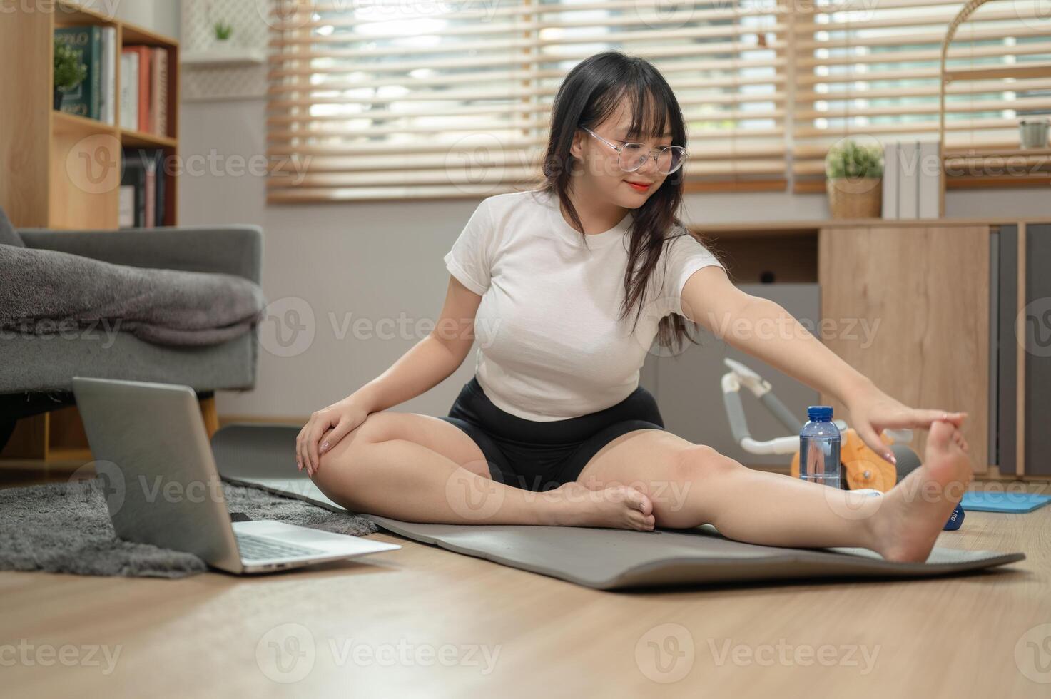 une en forme asiatique femme dans tenue de sport est Faire yoga à maison, Suivant le yoga Didacticiel en ligne. photo