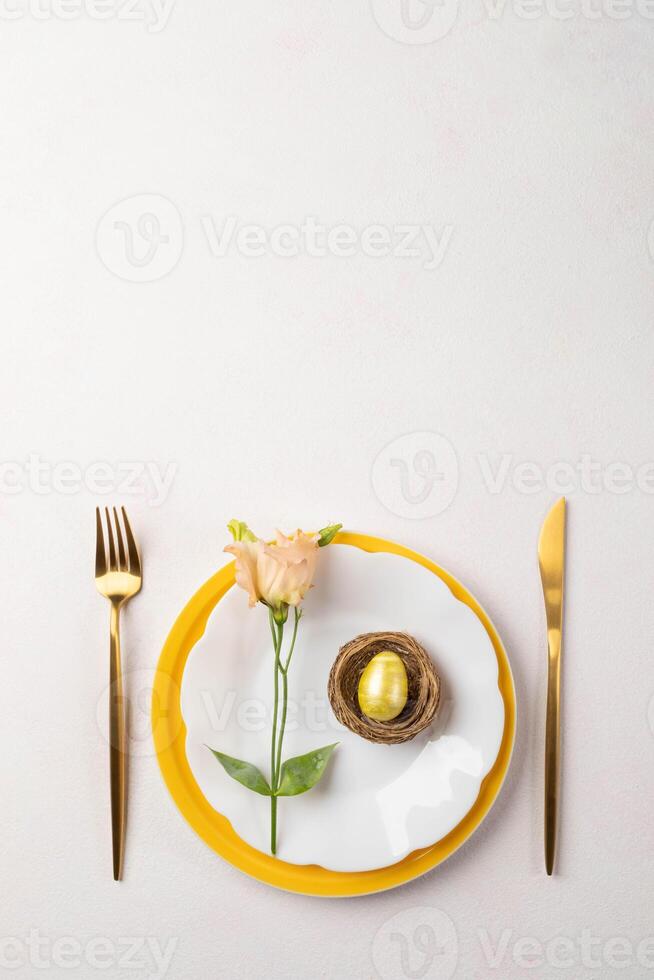 Pâques or Oeuf dans nid, pêche eustoma fleur sur assiettes, or coutellerie sur blanc rose. copie espace. photo