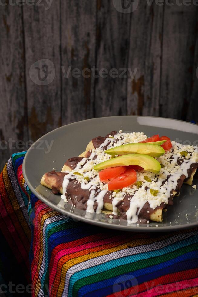 enfrijoladas servies dans un plat en argile. cuisine mexicaine typique. tacos aux haricots avec crème et fromage. photo